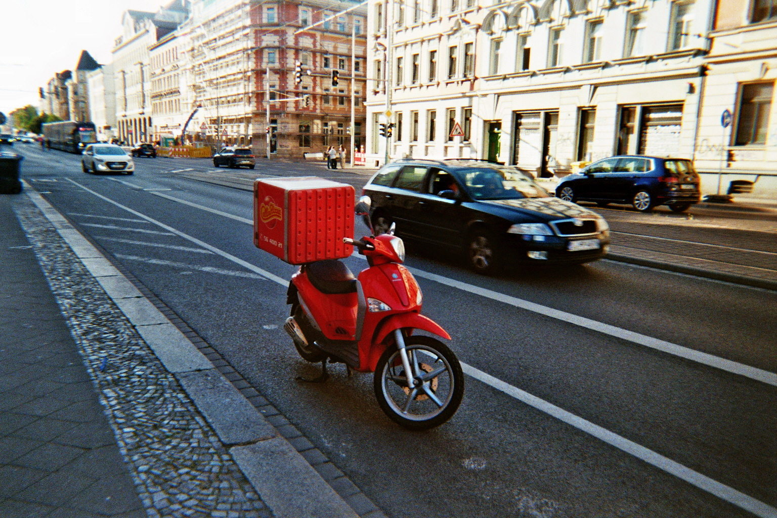 Moped and a moving car on a city street